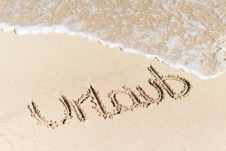 Foto Schriftzug Urlaub im Sand und darüber Wellen