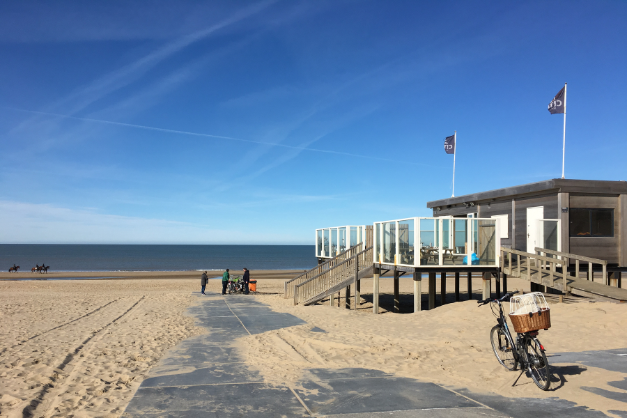 Foto Weg zum Strand mit Strandpavillion auf der rechten Seite im Hintergrund Meer und blauer Himmel
