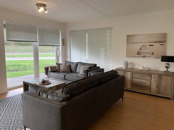 Foto Wohnzimmer mit Sofa, Sideboard und Blick auf die bodentiefen Terassentüren zum Garten